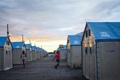 two people are walking in front of some small buildings with blue roofing on them