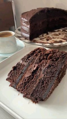 a slice of chocolate cake on a plate next to a large piece of chocolate cake