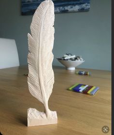 a white feather sculpture sitting on top of a wooden table