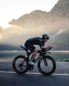 a man riding a bike down a road next to a lake