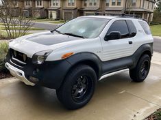 a silver and black four door suv parked on the side of a road in front of some houses