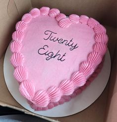 a pink heart shaped cake with the words twenty eight written on it in a box