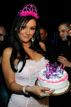 a woman in a white dress holding a cake with pink and purple frosting on it