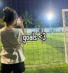 a woman taking a photo of a soccer goal
