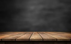 an empty wooden table in front of a dark background