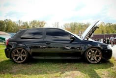 a black car with its hood open on the grass