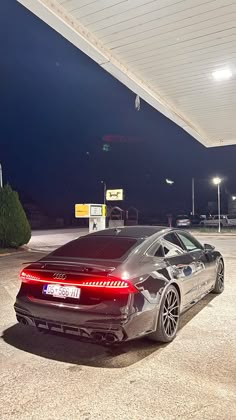 a car is parked in a parking lot at night with its lights on and it's tail light turned red