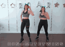 two women are dancing in front of a wall that says " dinomite twins "
