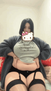 a woman wearing a hello kitty t-shirt is sitting on a bed
