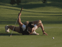 a man wearing a under armour hat is playing golf on a green