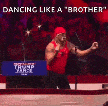 a man in a red tank top is dancing in front of a trump vance sign .