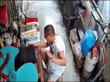 a man is sitting at a desk using a laptop and drinking water .