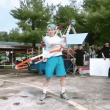 a man with blue hair is holding a hula hoop in a parking lot