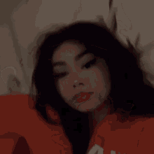 a girl is laying on a bed with her head on a pillow .