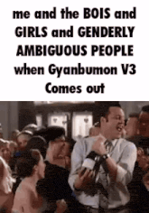 a man in a suit and tie is standing in front of a crowd of people and laughing .