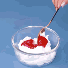 a glass bowl filled with whipped cream and strawberry sauce