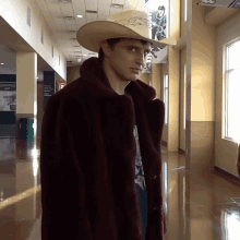 a young man wearing a cowboy hat and a fur coat