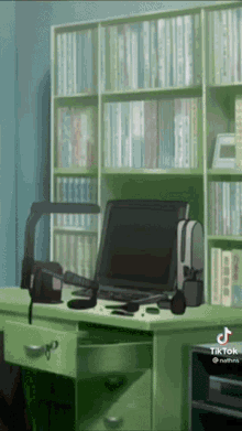 a green desk with a laptop and headphones on it in front of a bookshelf