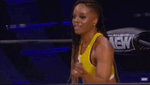 a woman is standing in a wrestling ring wearing a yellow tank top .