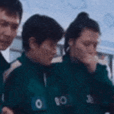 a group of people are standing next to each other wearing green jackets .
