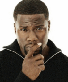 a man in a black sweater is thinking with his finger on his chin