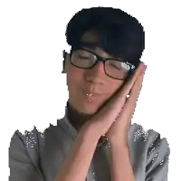 a man wearing glasses and a gray shirt is sleeping with his hands on his face