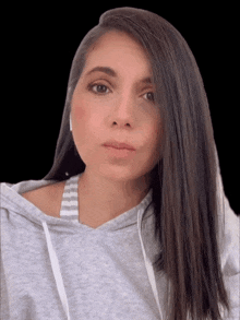 a woman with long dark hair wearing a grey hoodie and striped bra