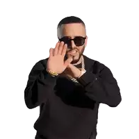 a man wearing sunglasses and a black sweater is making a stop sign with his hands .