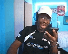 a man wearing headphones and a shirt that says scorpion is smiling while looking at his phone