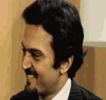 a man with a beard and a suit is smiling