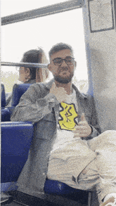 a man wearing glasses and a smiley face shirt gives the thumbs up