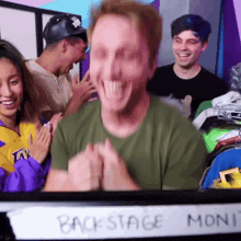 a man in a green shirt is smiling in front of a sign that says " backstage moni "