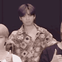 a man with purple hair is giving a thumbs up to two other people .