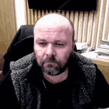 a bald man with a beard wearing a vest that says columbia