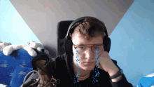 a young man wearing headphones and glasses is sitting in a chair