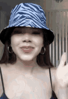 a woman wearing a blue and white zebra print bucket hat and hoop earrings .