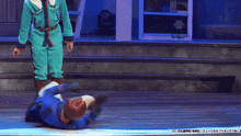 a man in a blue jumpsuit is laying on the floor