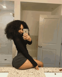 a woman is taking a selfie in the bathroom mirror .