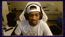 a man wearing headphones and a hat is sitting in a chair