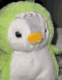 a stuffed penguin with a yellow beak is wearing a green hat