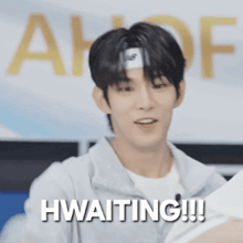 a young man with a headband on his head is holding a piece of paper and says waiting !!!
