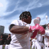 a baseball player wearing a white jersey and pink gloves stands in a crowd