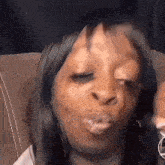 a woman is sitting on a couch making a funny face .