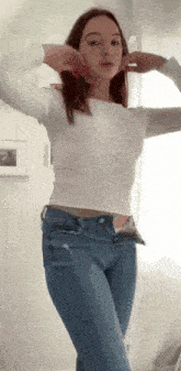 a woman in a white shirt and blue jeans is standing in a room