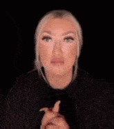 a woman is making a funny face with her hands in the dark .