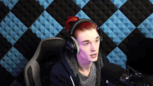 a young man with red hair wearing headphones and a gray shirt