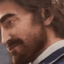 a close up of a man 's face with a beard in a suit .