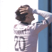 a soccer player wearing a number 20 jersey holds his hand to his head
