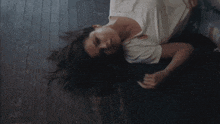 a woman in a white shirt and blue jeans is laying on the floor