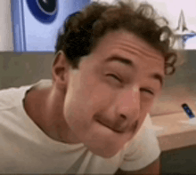 a young man with curly hair is making a funny face .